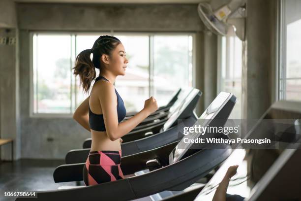 young women in sportswear running on treadmill at gym - treadmill fotografías e imágenes de stock