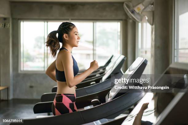 young women in sportswear running on treadmill at gym - トレッドミル　女性 ストックフォトと画像