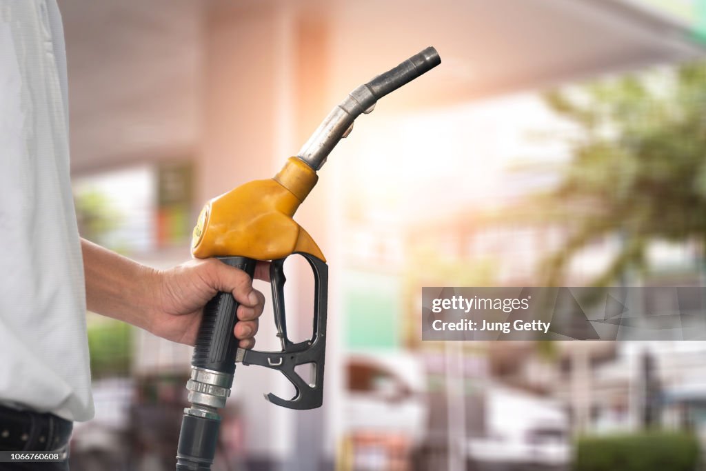 Pumping equipment gas at gas station. Close up of a hand holding fuel nozzle