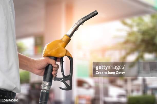 pumping equipment gas at gas station. close up of a hand holding fuel nozzle - service station stock pictures, royalty-free photos & images