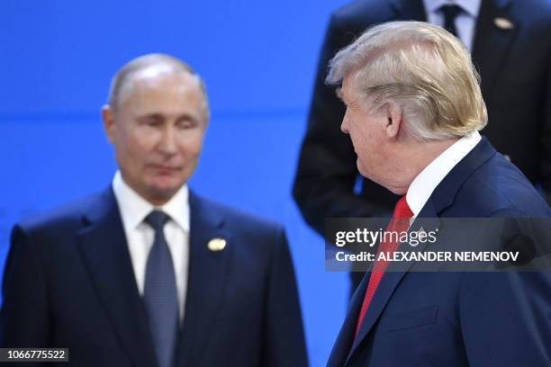 President Donald Trump looks at Russia's President Vladimir Putin as they take their places for a family photo, during the G20 Leaders' Summit in...