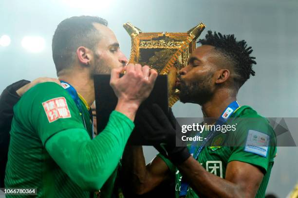 Beijing Guoan's Renato Augusto and Cedric Bakambo kiss the trophy after winning the Chinese FA Cup final after drawing 2-2 in the second leg with...