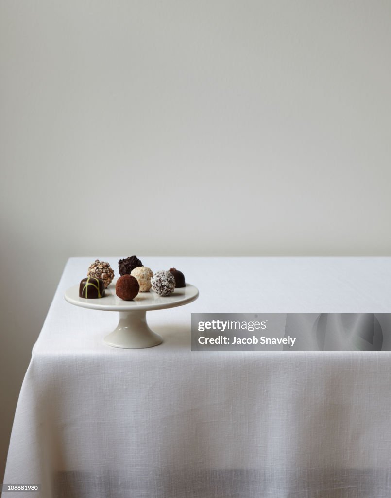 Confections displayed on white linen table.
