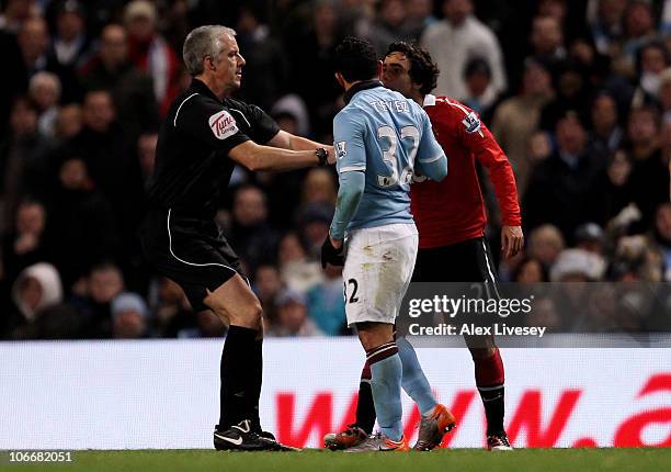 Referee Chris Foy separates Rafael Da Silva of Manchester United and Carlos Tevez of Manchester City during the Barclays Premier League match between...