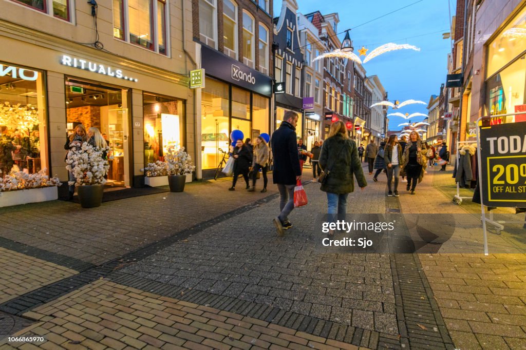 Diezestraat shopping street in Zwolle during a cold winter night, People are walking on the street and looking at the shop windows.