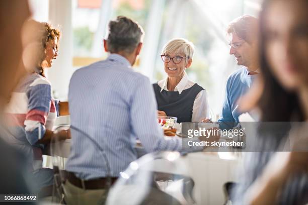 happy senior businesswoman talking to her colleagues on a lunch break. - senior lunch stock pictures, royalty-free photos & images