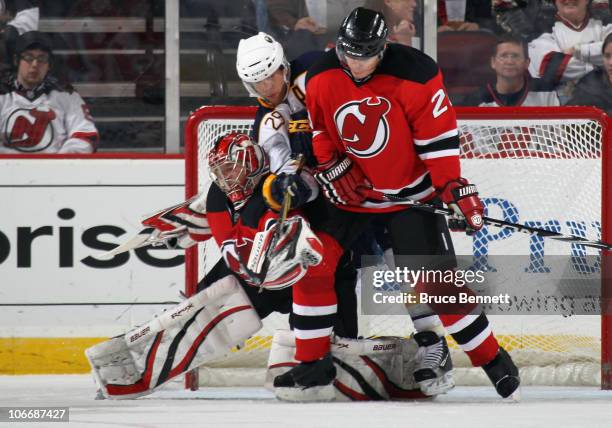 Jason Pominville of the Buffalo Sabres looks to deflect the puck in front of goaltender Johan Hedberg and Anton Volchenkov of the New Jersey Devils...