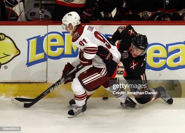 Jonathan Toews of the Chicago Blackhawks slips to the ice as he battles for the puck with Kyle Turris of the Phoenix Coyotes at the United Center on...