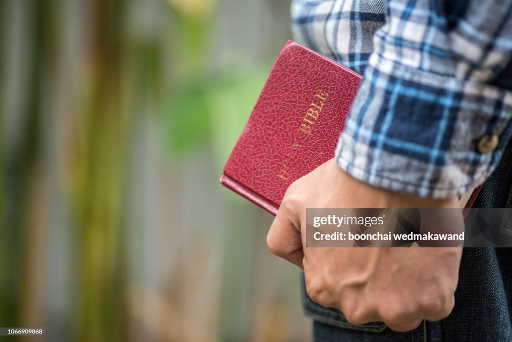 Human hand placed on the Bible, pray to God.