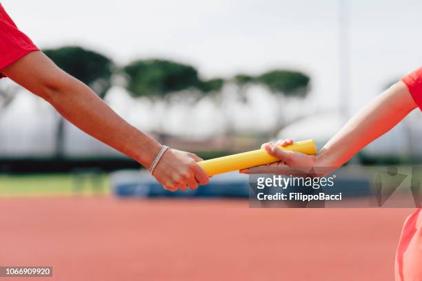 passing the relay baton on the track field - passing - sport stock pictures, royalty-free photos & images