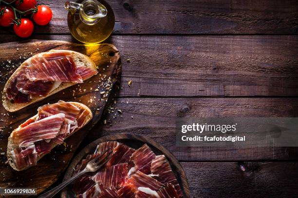 delicious iberico ham tray shot on rustic wooden table - serrano ham stock pictures, royalty-free photos & images