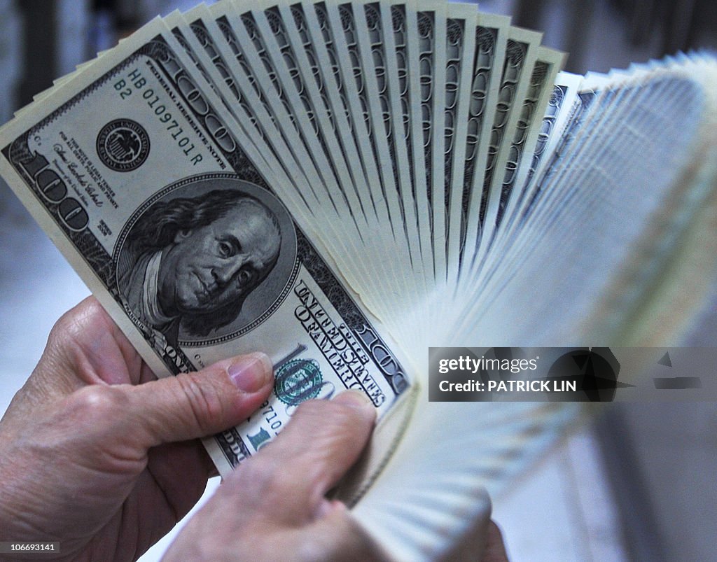 A clerk counts US dollar bills at a bank