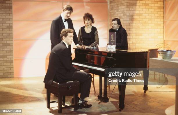 Comic actors Hugh Laurie, Stephen Fry, Fiona Gillies and Kevin McNally standing around a piano in a sketch from the BBC television series 'A Bit of...