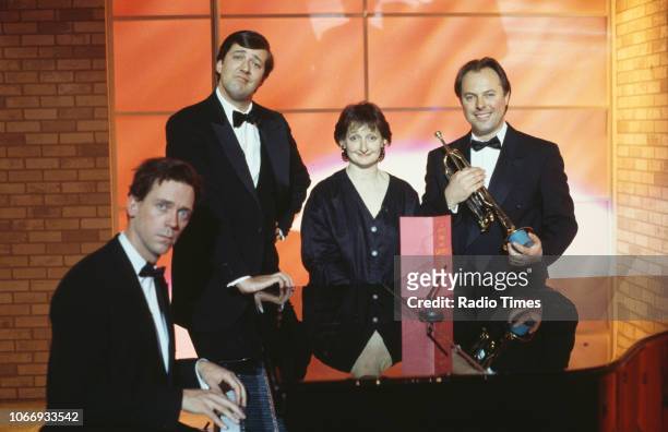 Comic actors Hugh Laurie, Stephen Fry, Janine Duvitski and Robert Daws standing around a piano in a sketch from the BBC television series 'A Bit of...
