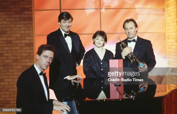 Comic actors Hugh Laurie, Stephen Fry, Janine Duvitski and Robert Daws standing around a piano in a sketch from the BBC television series 'A Bit of...