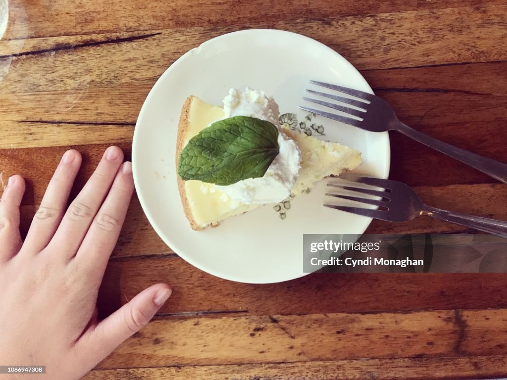 Child's Hand Next to a Plate of Key Lime Pie