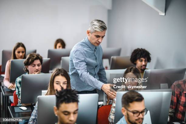 profesor ayudar a sus alumnos en una clase de informática. - male professor with students fotografías e imágenes de stock