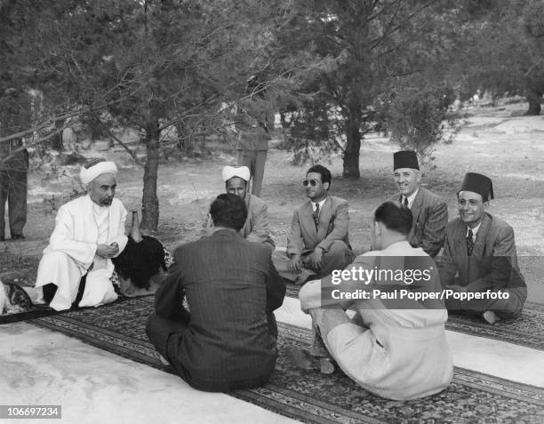 King Abdullah I of Transjordan holds a conference in the grounds of Raghadan Palace in Amman, Jordan, 14th June 1948. He is resting his arm on a...