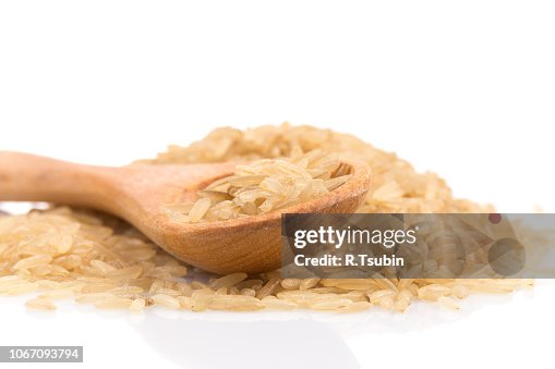 Brown rice over the spoon on a white background Brown rice over the spoon on a white background