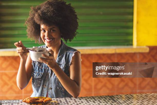 portret van afro braziliaanse vrouw eten van gebakken vis met acai, een combinatie van de typische gerechten van amazone keuken - belém brazilië stockfoto's en -beelden