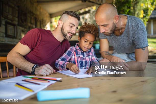 joli couple hétérosexuel fait ses devoirs avec leur fille adoptive - adoption photos et images de collection