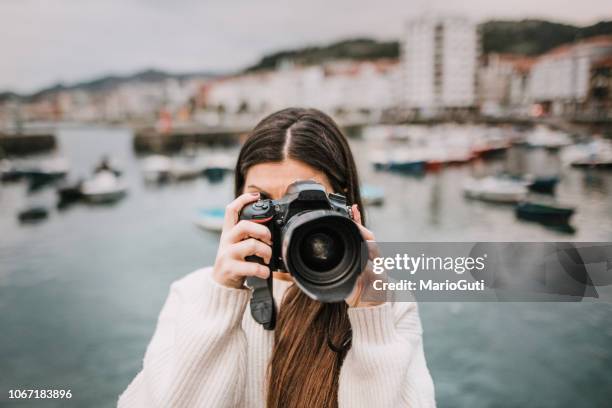 junge frau, die eine aufnahme mit einer modernen dslr-kamera - spiegelreflexkamera stock-fotos und bilder