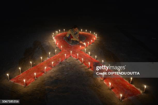 An Indian sex worker lights candles forming the shape of a ribbon as part of an awareness event on the occasion of World AIDS Day in Siliguri on...