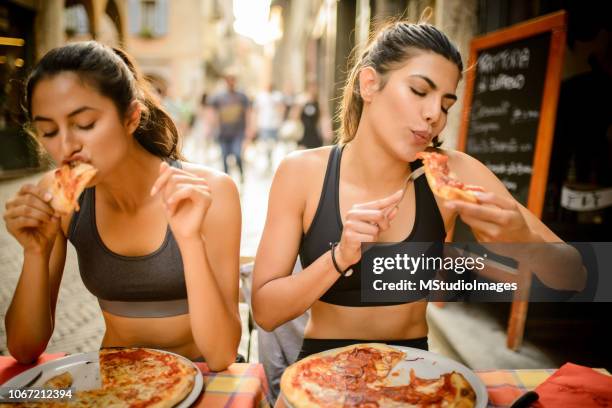 zwei sportliche frau pizza essen. - italy training stock-fotos und bilder
