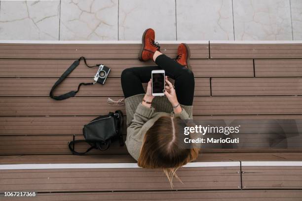 young woman with smartphone sitting on staircase - mobile phone reading low angle stock pictures, royalty-free photos & images