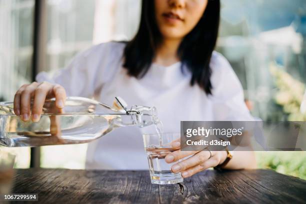 woman pouring water from bottle into the glass at a outdoor cafe - thirsty stock pictures, royalty-free photos & images