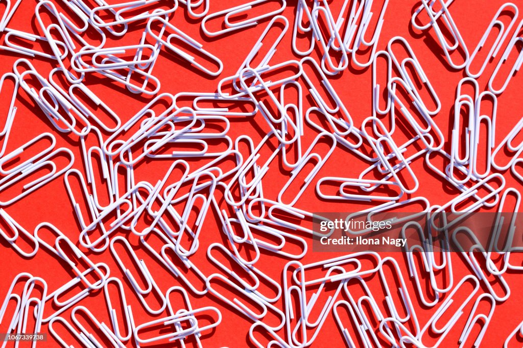 White paper clips on red background