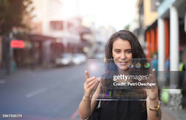 a young woman looking at financial figures on a tablet.. - hologram projection stock pictures, royalty-free photos & images