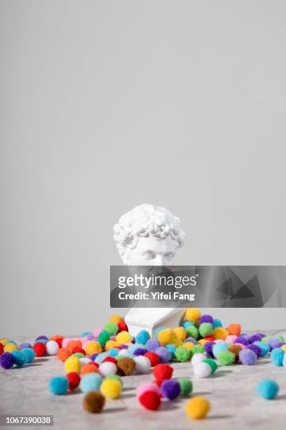 playful portrait of head sculpture surrounded by colourful objects - umgeben stock-fotos und bilder