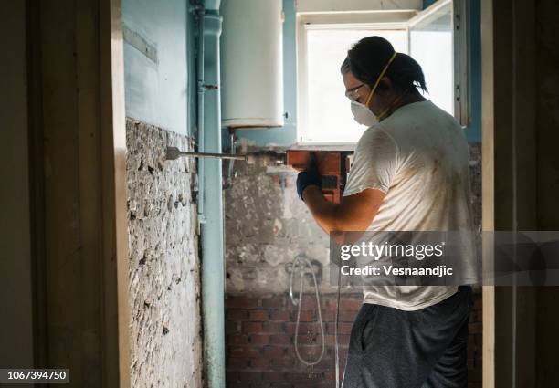 men taking off old tile from wall with jackhammer - jackhammer stock pictures, royalty-free photos & images
