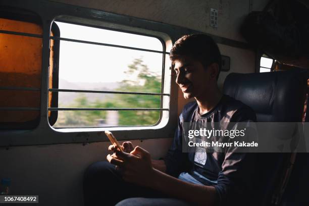 teenage boy using mobile phone while travelling on train - india train stock pictures, royalty-free photos & images