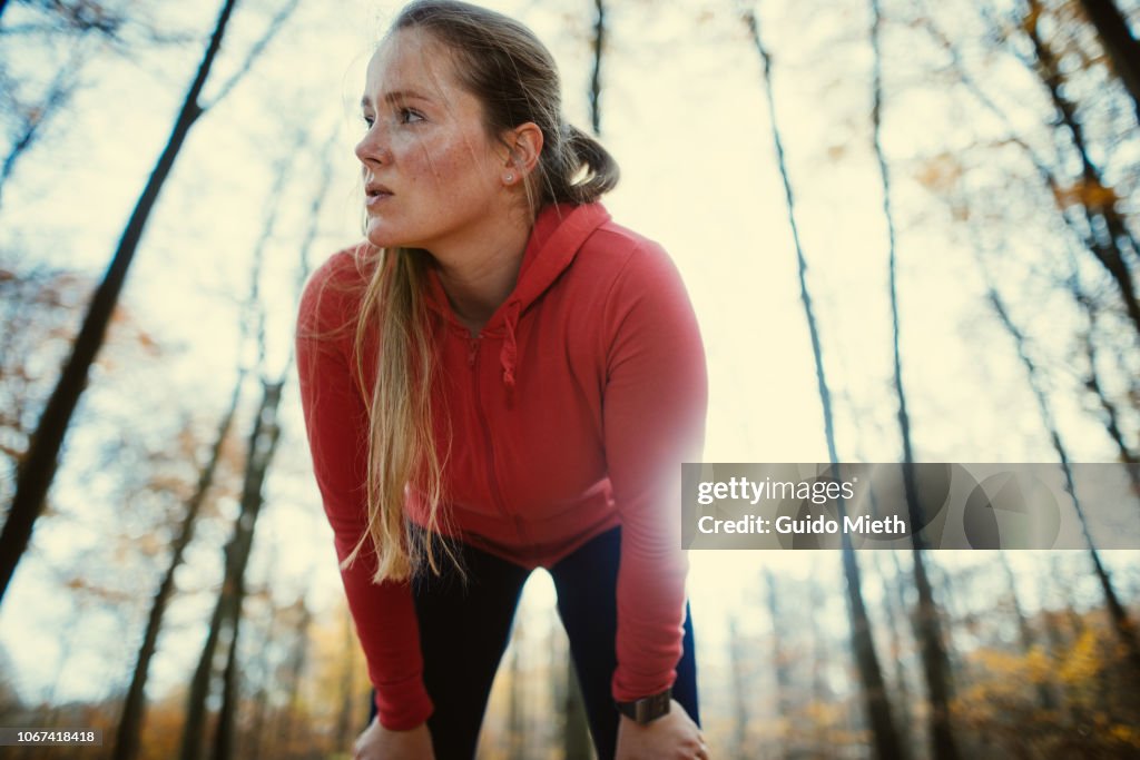 Exhausted woman after jogging in autumnal park.