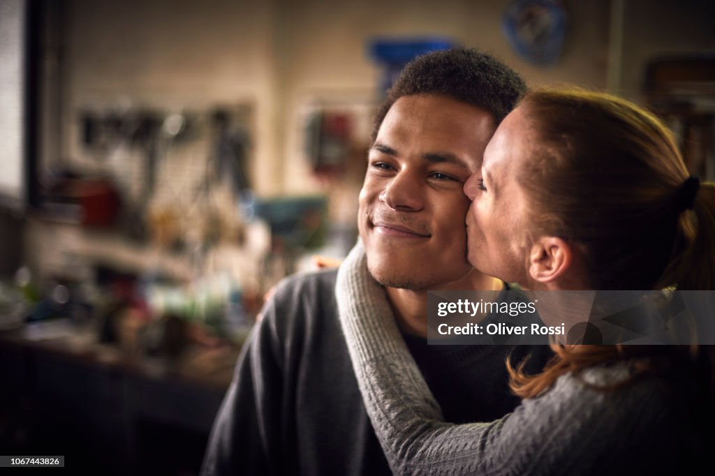Happy mother kissing son in a workshop