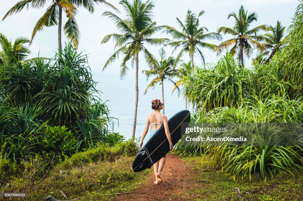 Female surfer carries longboard