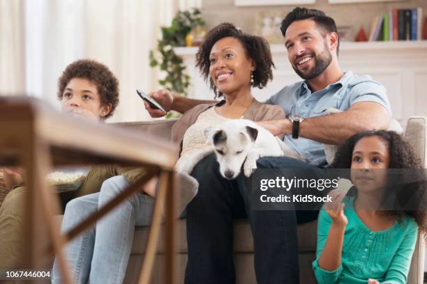 multi-ethnic family having fun and watching tv - family tv pet stock pictures, royalty-free photos & images