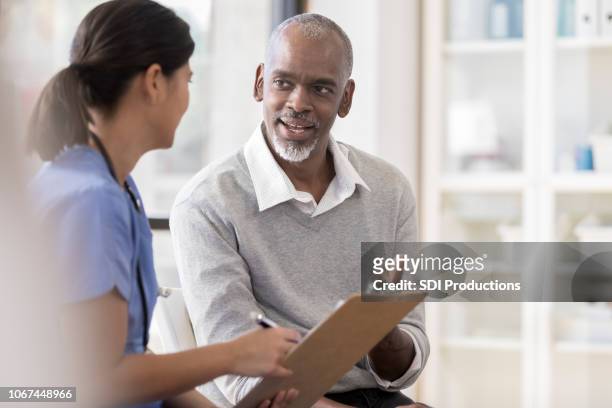 senior man discusses diagnosis with doctor - males stock pictures, royalty-free photos & images