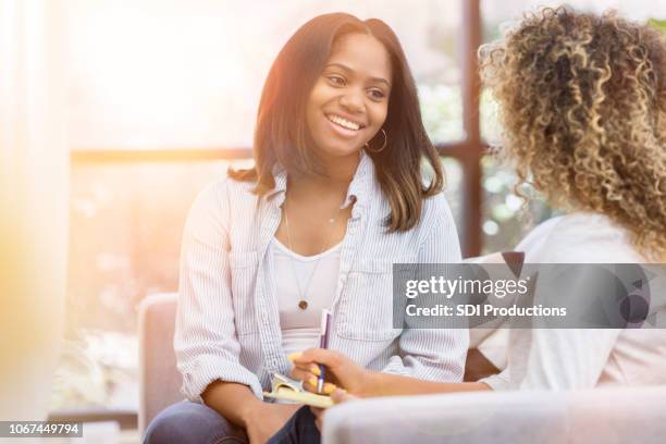 a mid-adult woman smiles during a therapy session in a bright office - wellbeing support stock pictures, royalty-free photos & images