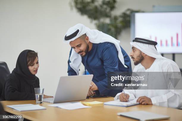 männlichen und weiblichen kollegen diskutieren über laptop - emirati guy using laptop stock-fotos und bilder