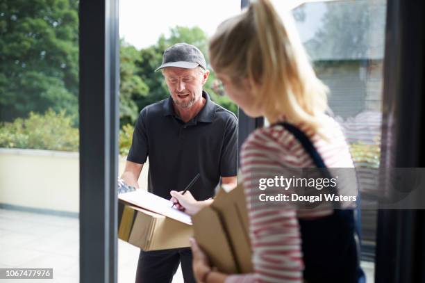 courier worker delivering parcel to woman. - postbode stockfoto's en -beelden