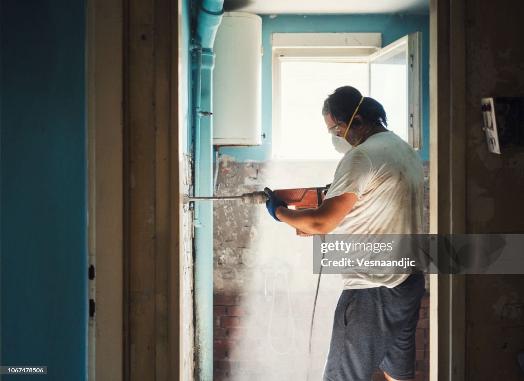 Men taking off old tile from wall with jackhammer