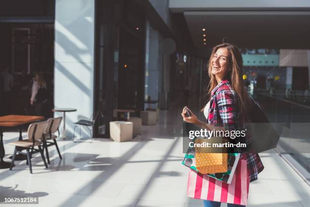 glückliche frau in der shopping mall in die kamera lächeln - frau tüte einkaufen stock-fotos und bilder