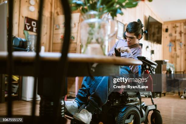 confident young man in wheelchair at home - motorized wheelchair stock pictures, royalty-free photos & images