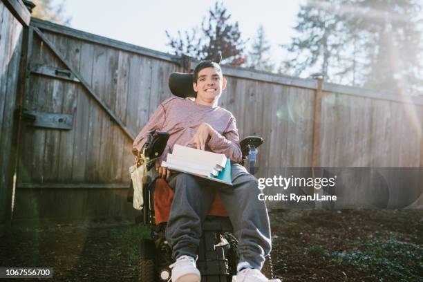 confident young man in wheelchair with textbooks - motorized wheelchair stock pictures, royalty-free photos & images