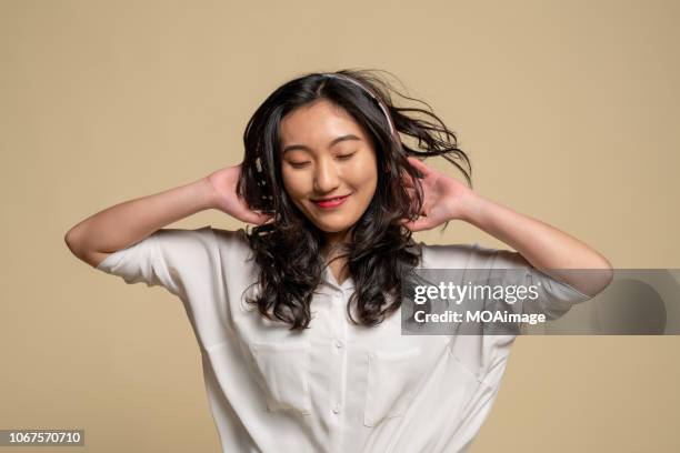 a young asian girl is listening to music - portrait beige background stock pictures, royalty-free photos & images