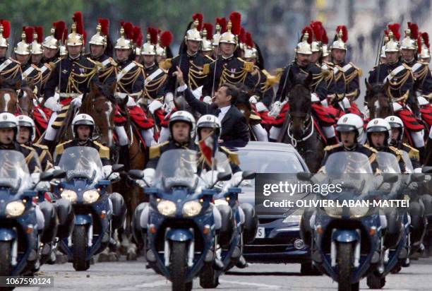 New French President Nicolas Sarkozy waves from a car on his way to rekindle the flame on the tomb of the unknown soldier beneath the Arc de...