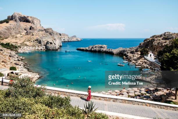 woman walking to saint paul's bay in lindos, greece - rhodes,_new_south_wales stock pictures, royalty-free photos & images